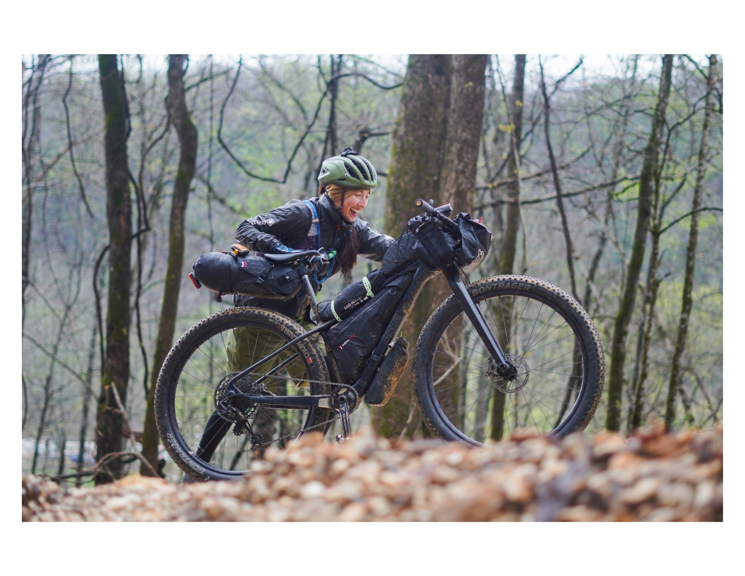 candid photograph of female cyclists pushing her loaded bike up a hill in arkansas during DOOM the ultra bikepacking race