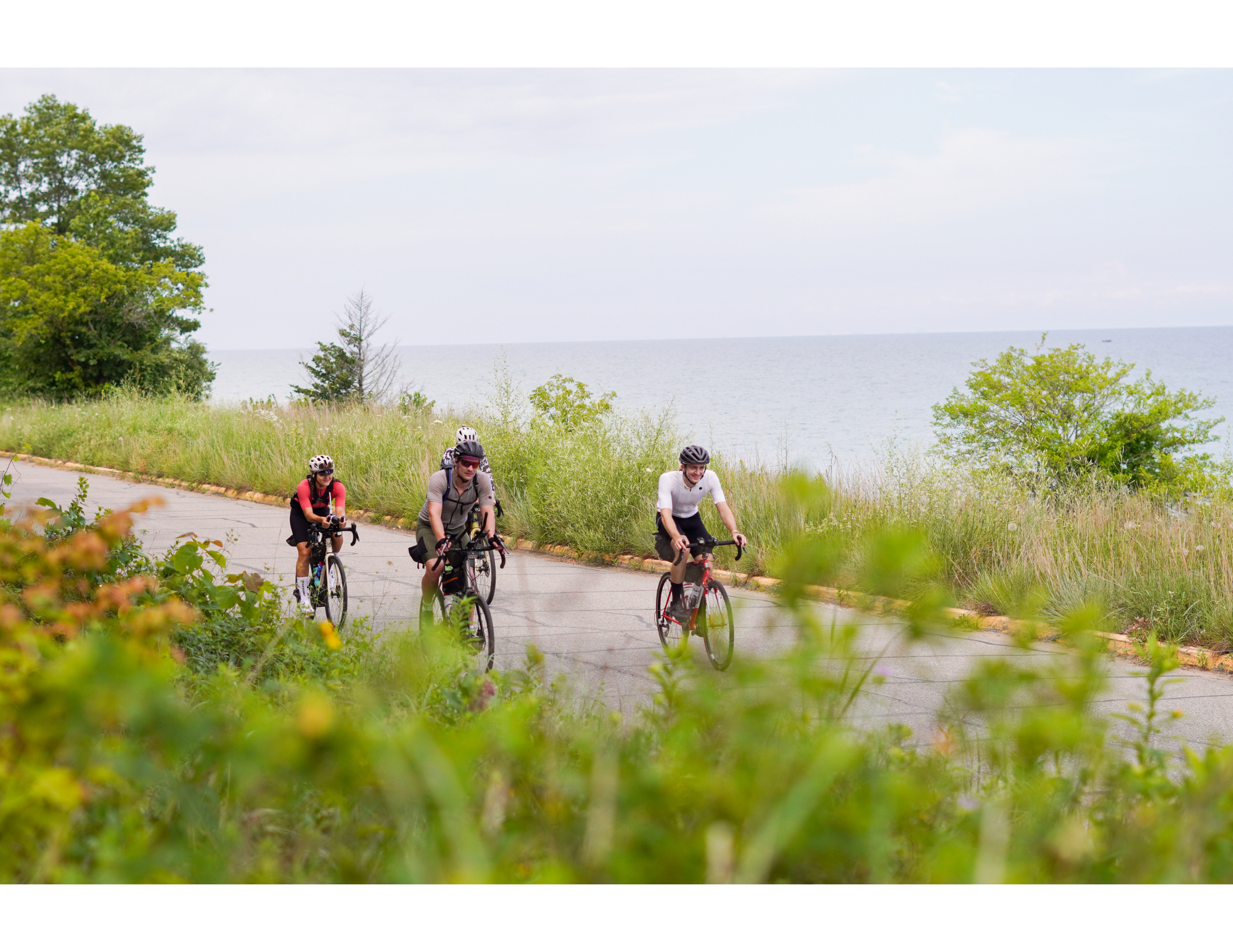 candid photograph of three ultra cyclist riding through the indiana sand dunes in front of lake michigan during the mishigami bike race