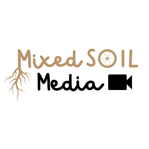 mixed soil letters with roots coming out of the m and a bike wheel as the 0 all in tan and the letters for media in black with a black video camera icon next to it under mised soil